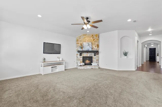 a view of a livingroom with a flat screen tv a ceiling fan window and a kitchen