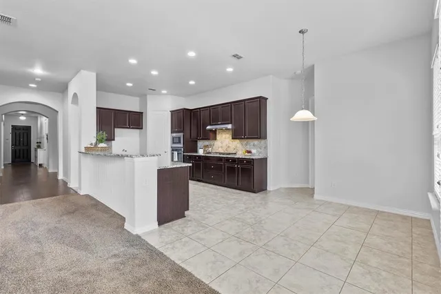 a kitchen with stainless steel appliances granite countertop a refrigerator and a stove top oven