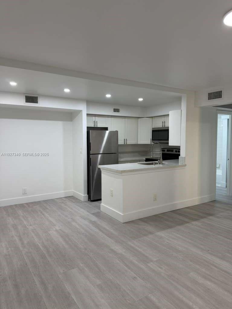 a view of kitchen with kitchen island white cabinets and stainless steel appliances