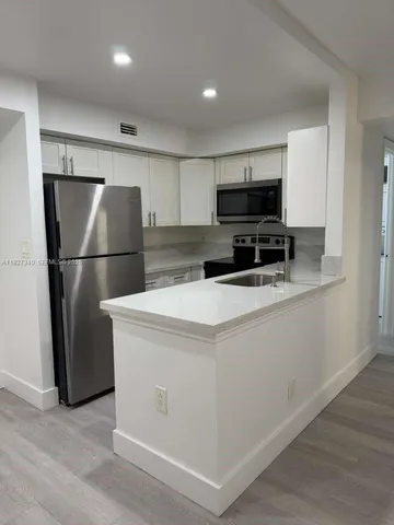 a kitchen with kitchen island a refrigerator and a stove top oven