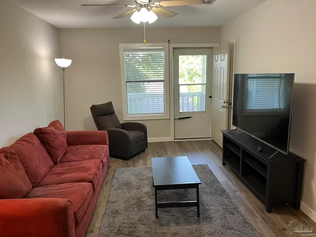 a living room with furniture a flat screen tv and a window