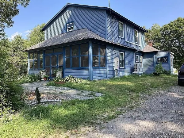 a view of a house with a yard plants and large tree