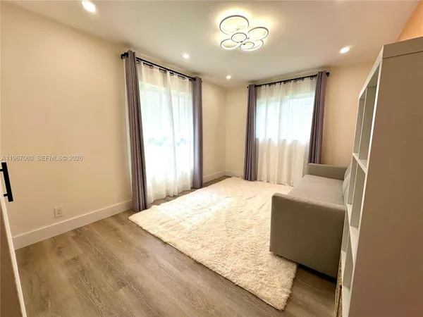 a bedroom with a bed and a dresser with wooden floor