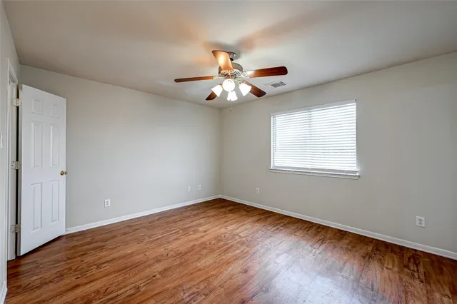 a view of an empty room with window and wooden floor