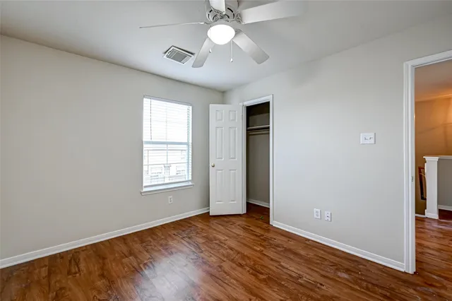 a view of an empty room with window and wooden floor