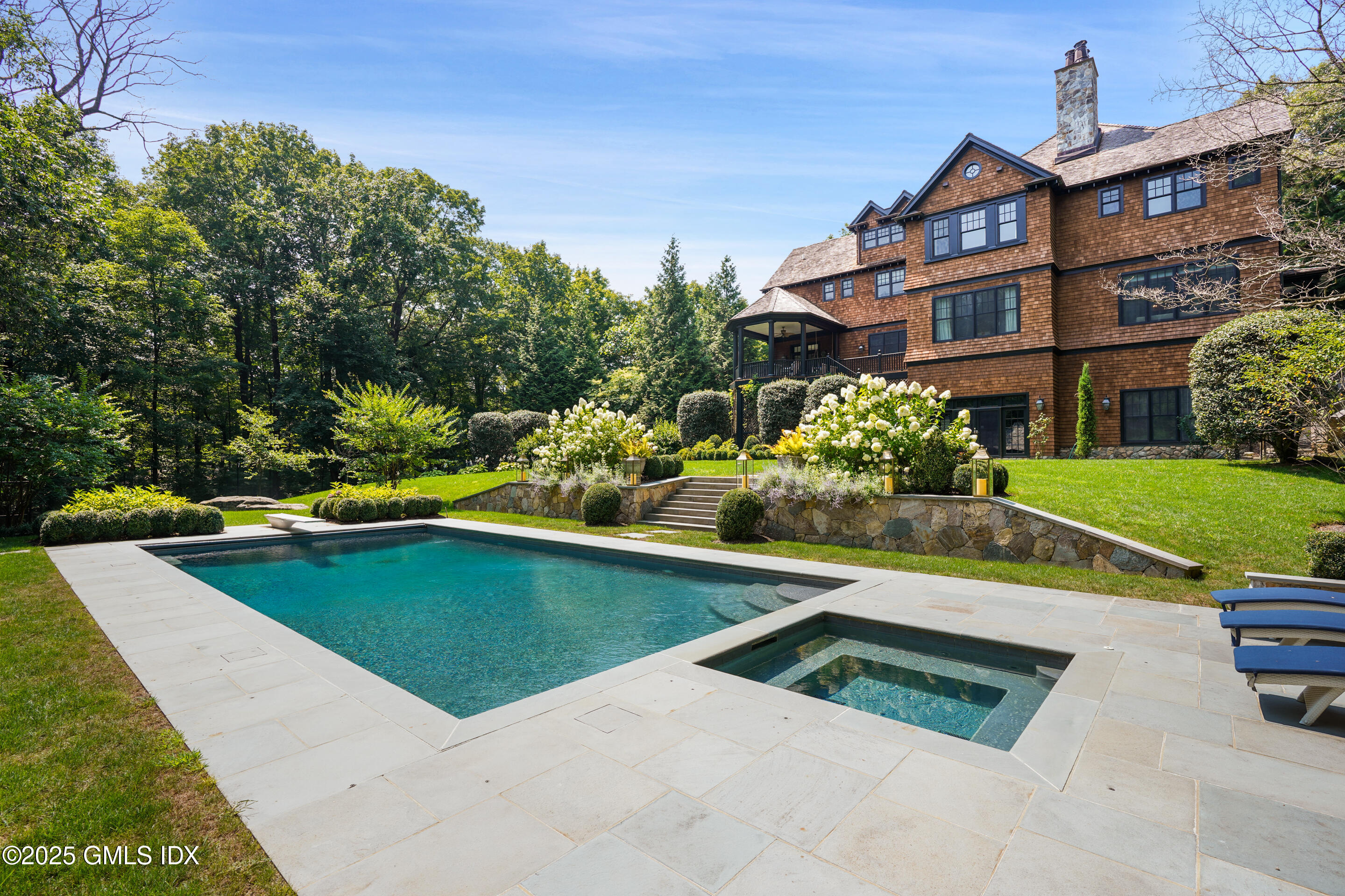 a view of a house with pool plants and trees in the background