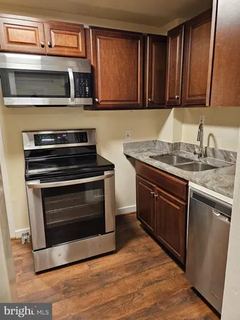 a kitchen with granite countertop a sink dishwasher a stove and cabinets