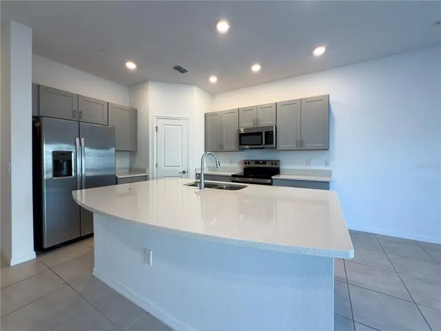 a large white kitchen with kitchen island a stove a sink and a refrigerator