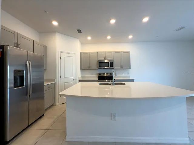 a large kitchen with a large counter top stainless steel appliances and cabinets