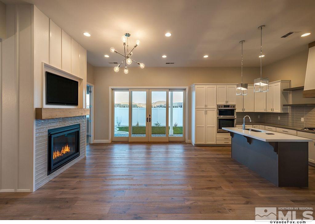 6430 Bonde Lane Reno, NV 89511 - Photo 2 of 9 a open kitchen with kitchen island granite countertop a stove top oven a sink and a fireplace