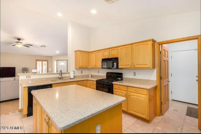 a kitchen with stainless steel appliances granite countertop a stove top oven a sink a refrigerator and white cabinets with wooden floor