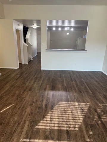 a view of an empty room with wooden floor and a fireplace