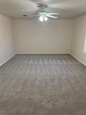 an empty room with chandelier fan and windows