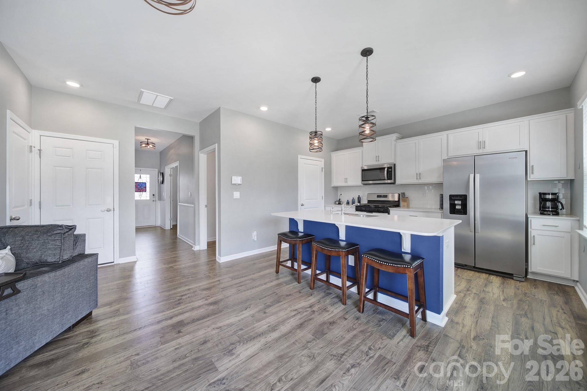 107 Spring Hall Court Troutman, NC 28166 - Photo 5 of 28 a kitchen with stainless steel appliances kitchen island granite countertop a dining table chairs refrigerator and sink