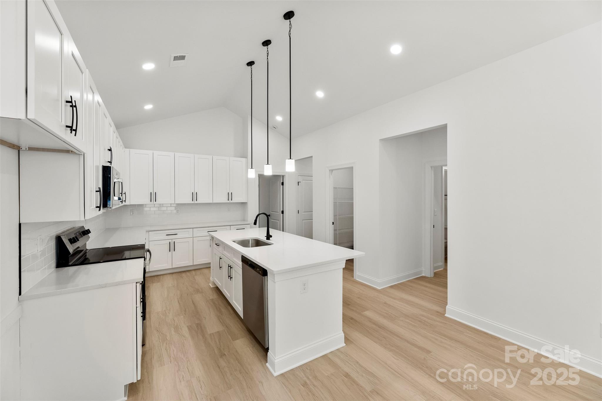 90 Sumner Avenue Northwest Concord, NC 28027 - Photo 5 of 40 a kitchen with stainless steel appliances a sink a stove a refrigerator and white cabinets with wooden floor
