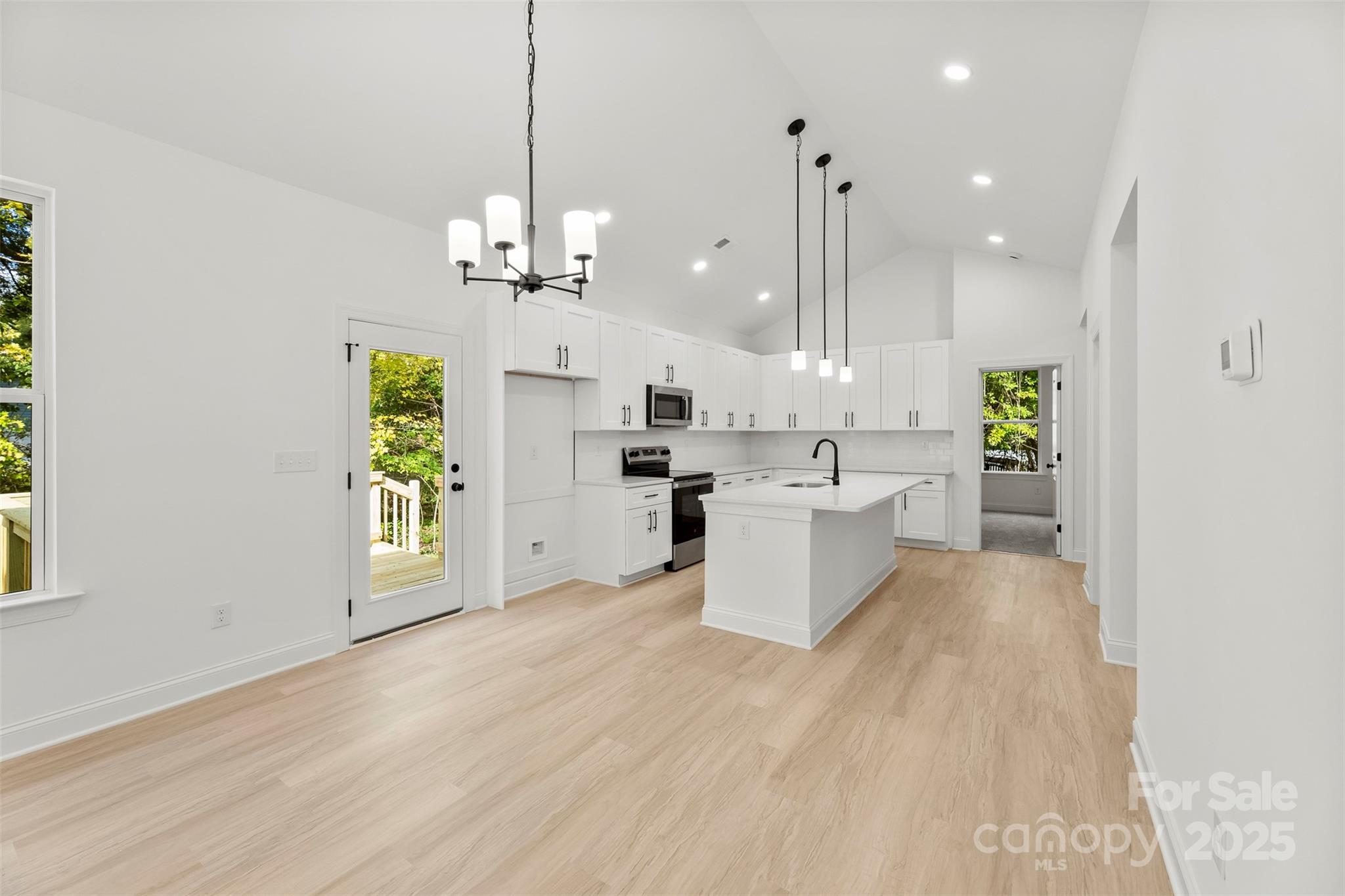 90 Sumner Avenue Northwest Concord, NC 28027 - Photo 6 of 40 a view of a kitchen with kitchen island a refrigerator a sink dishwasher a dining table and chairs with wooden floor