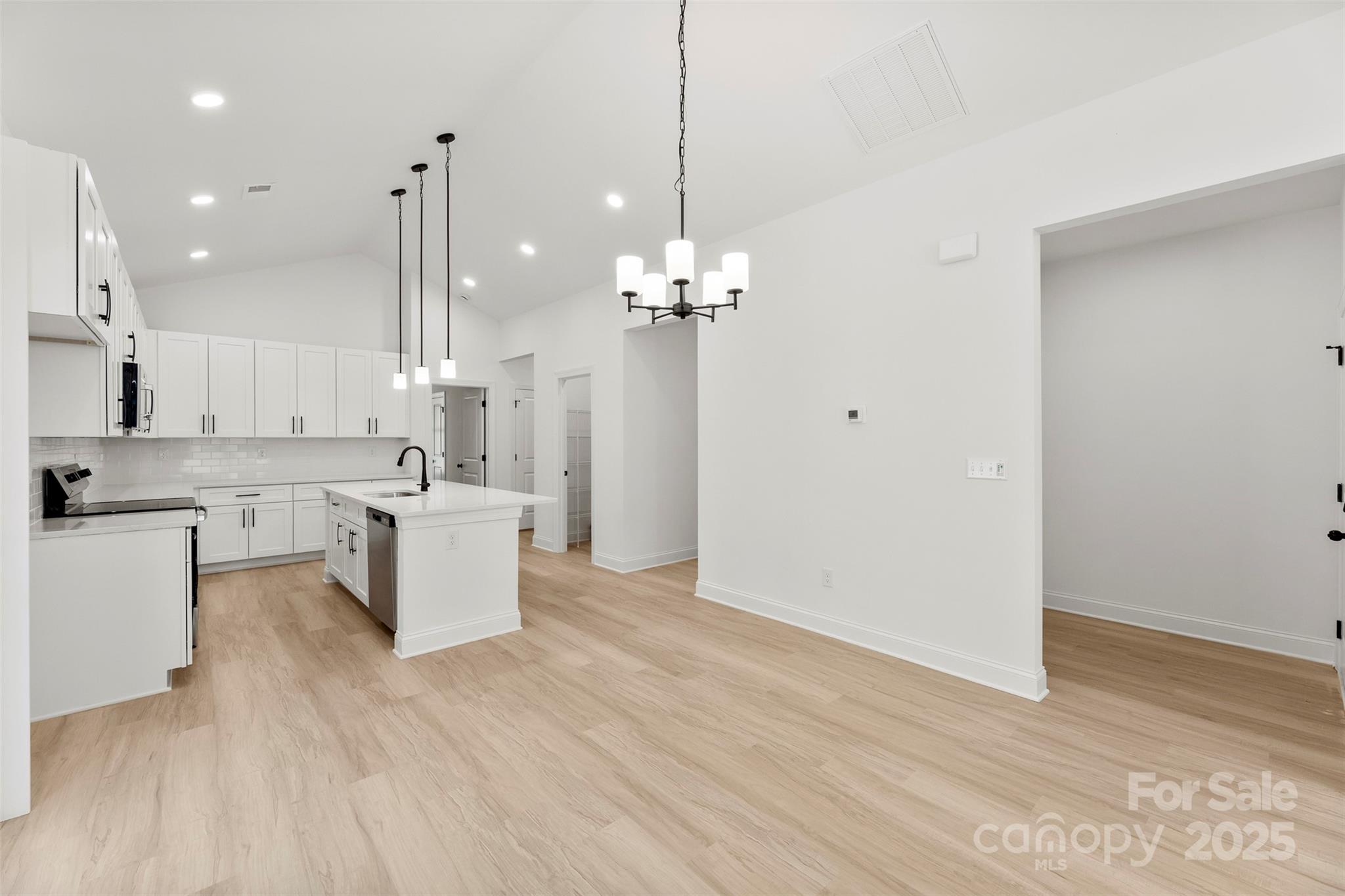 90 Sumner Avenue Northwest Concord, NC 28027 - Photo 7 of 40 a large white kitchen with a large island oven a sink dishwasher and a fireplace with wooden floor