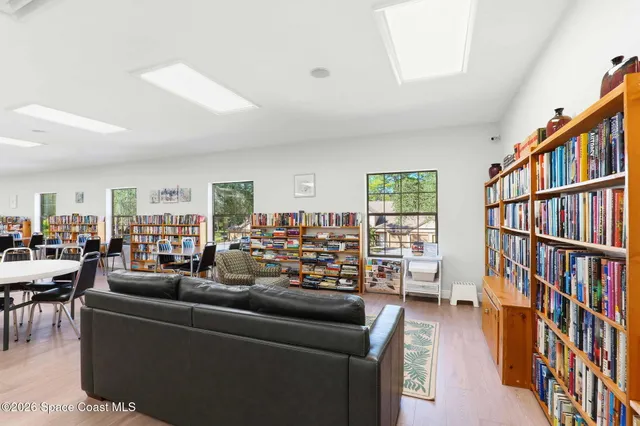 a living room with furniture lots of books and a window