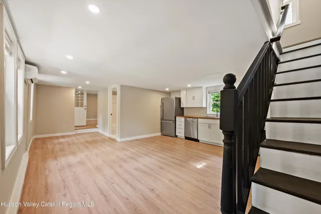 a view of kitchen and empty room with wooden floor