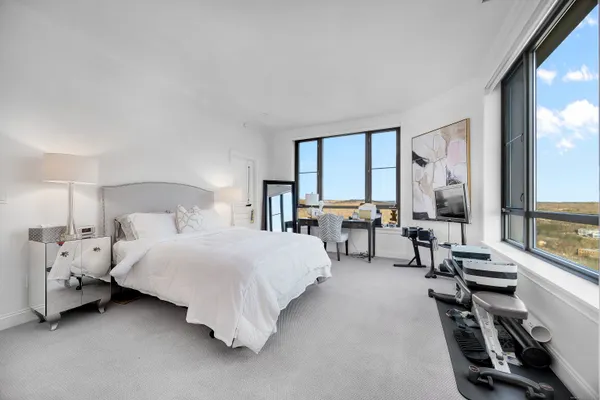 a bedroom with a bed and large windows