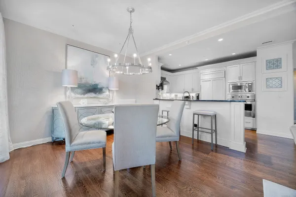 a view of a dining room and livingroom with furniture wooden floor kitchen view and a chandelier