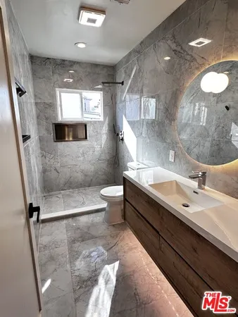a bathroom with a double vanity sink toilet mirror and bathtub