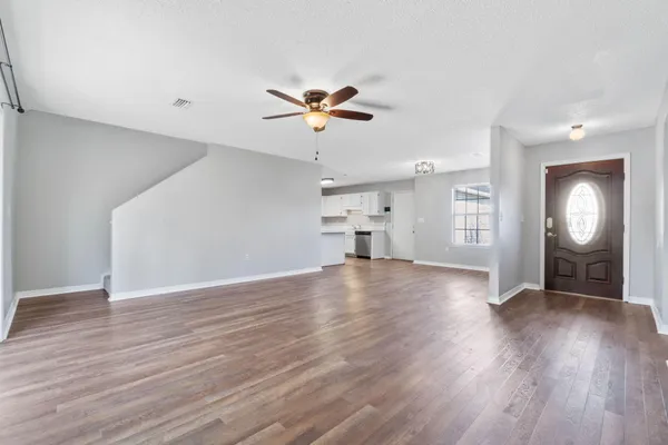 a view of a room with wooden floor and a ceiling fan