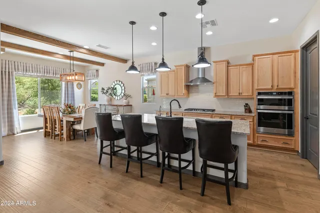 a kitchen with stainless steel appliances granite countertop table chairs and a view of living room