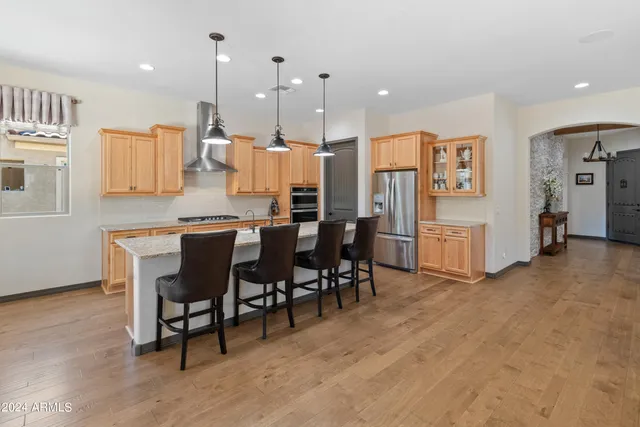 a dining hall with stainless steel appliances kitchen island granite countertop a table chairs and a refrigerator