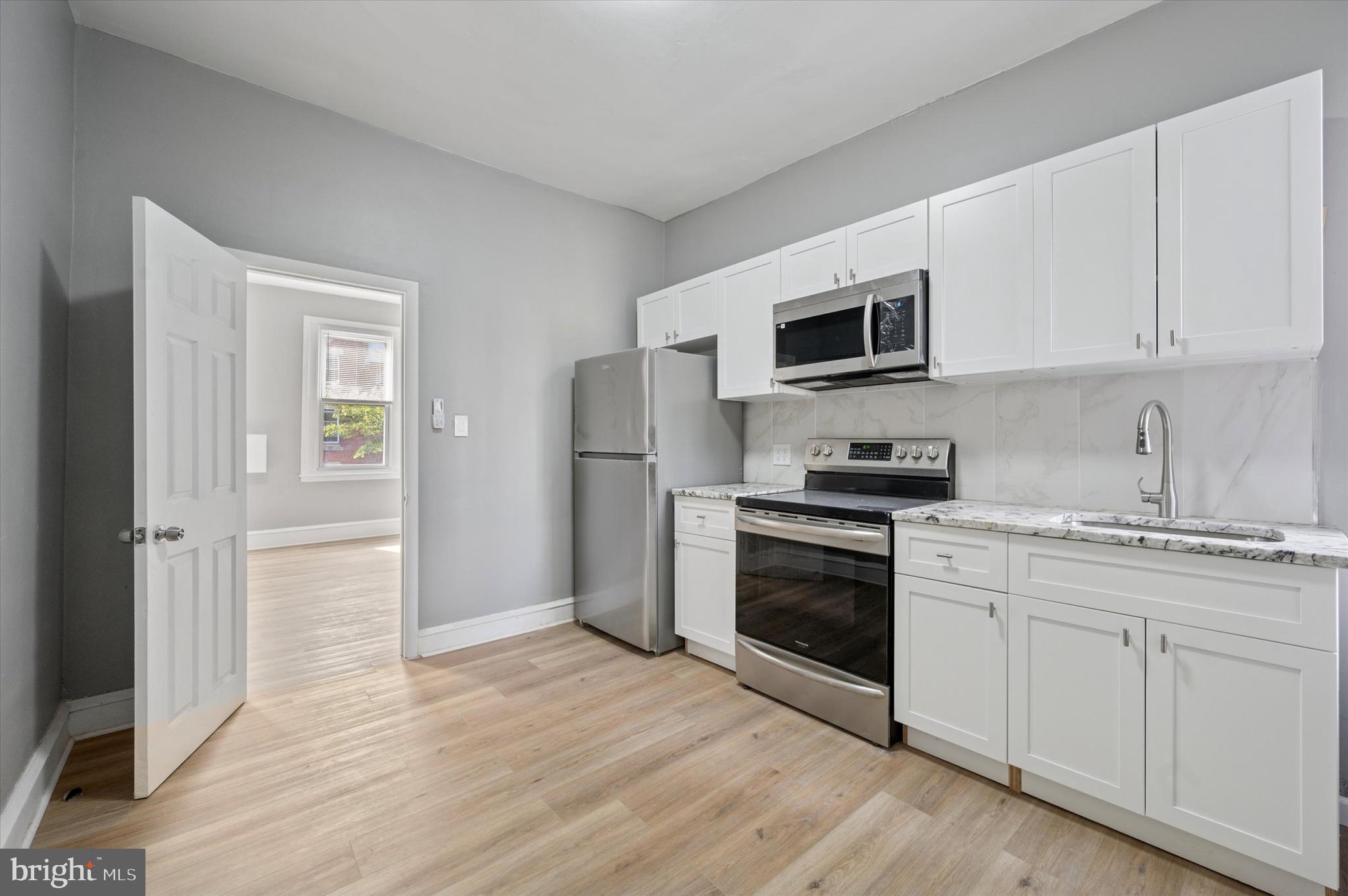249 South 44th Street, Unit 4 Philadelphia, PA 19104 - Photo 5 of 25 a kitchen with granite countertop a refrigerator and a stove top oven