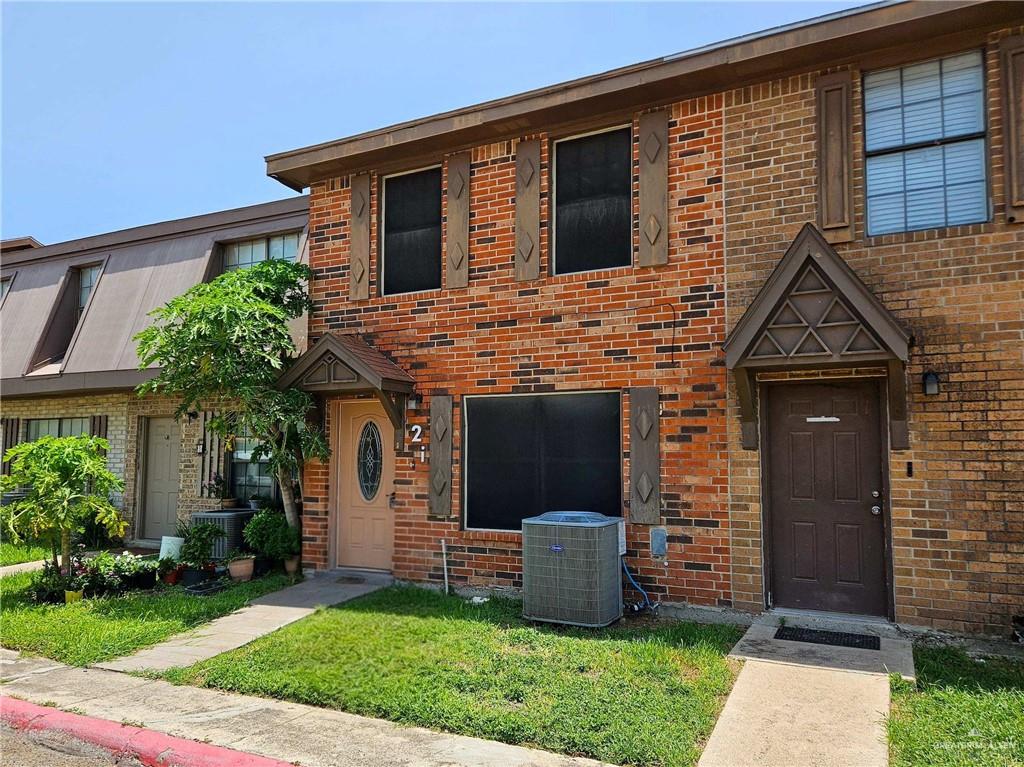 2201 South Jackson Road, Unit 2I Pharr, TX 78577 - Photo 3 of 23 Brick exterior townhome featuring a decorative brown entry door with an ornate overhang