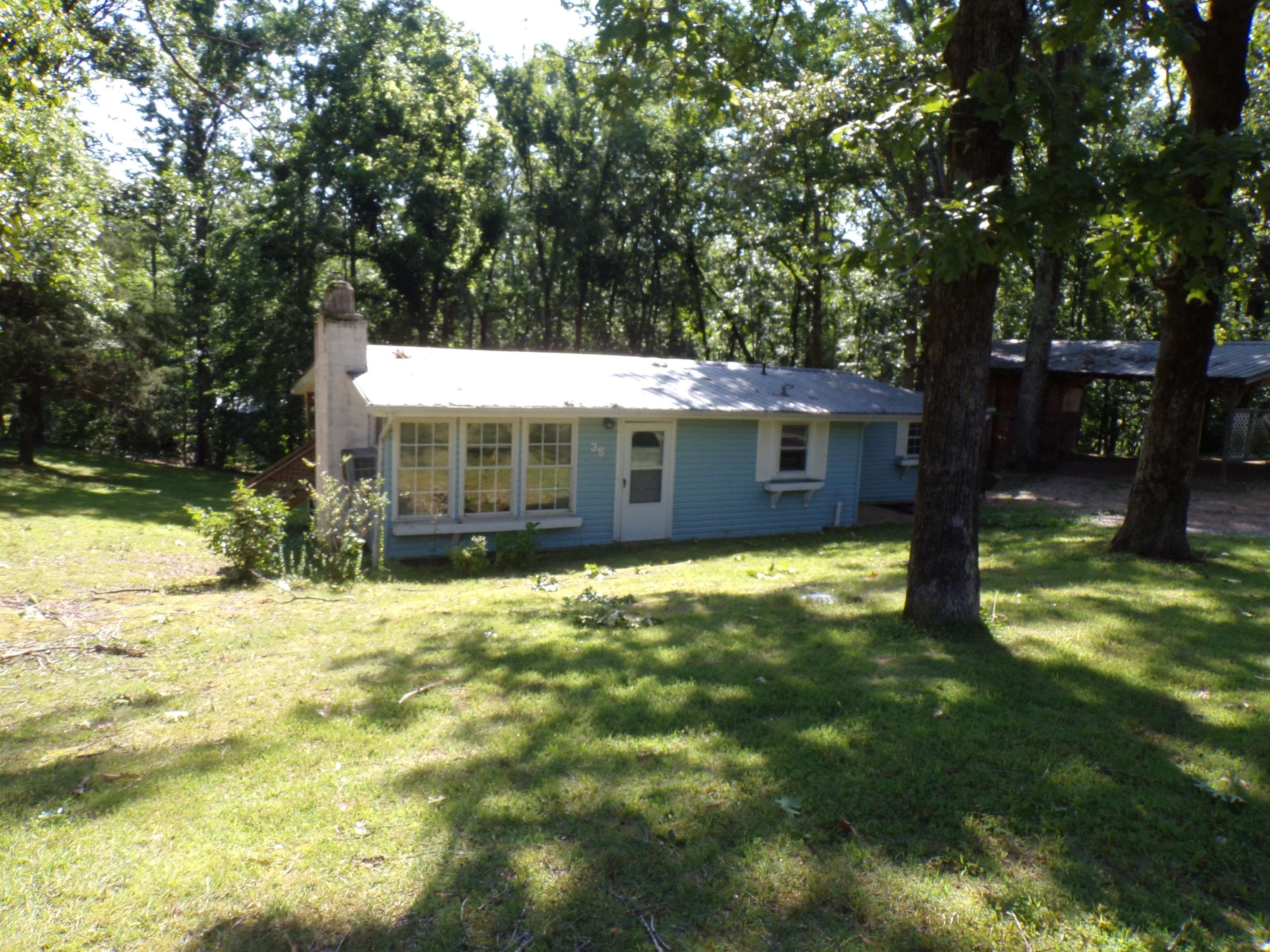 35 Cr 341 Road Iuka, MS 38852 - Photo 2 of 15 Light blue exterior featuring a prominent chimney, a white front door, and a row of large windows