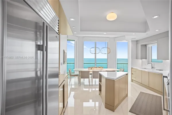 a room with stainless steel appliances kitchen island granite countertop a refrigerator and a sink