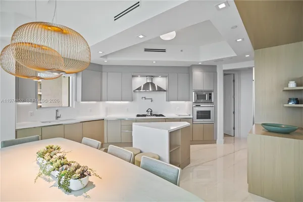 a kitchen with stainless steel appliances a sink a stove a refrigerator cabinets and dining table