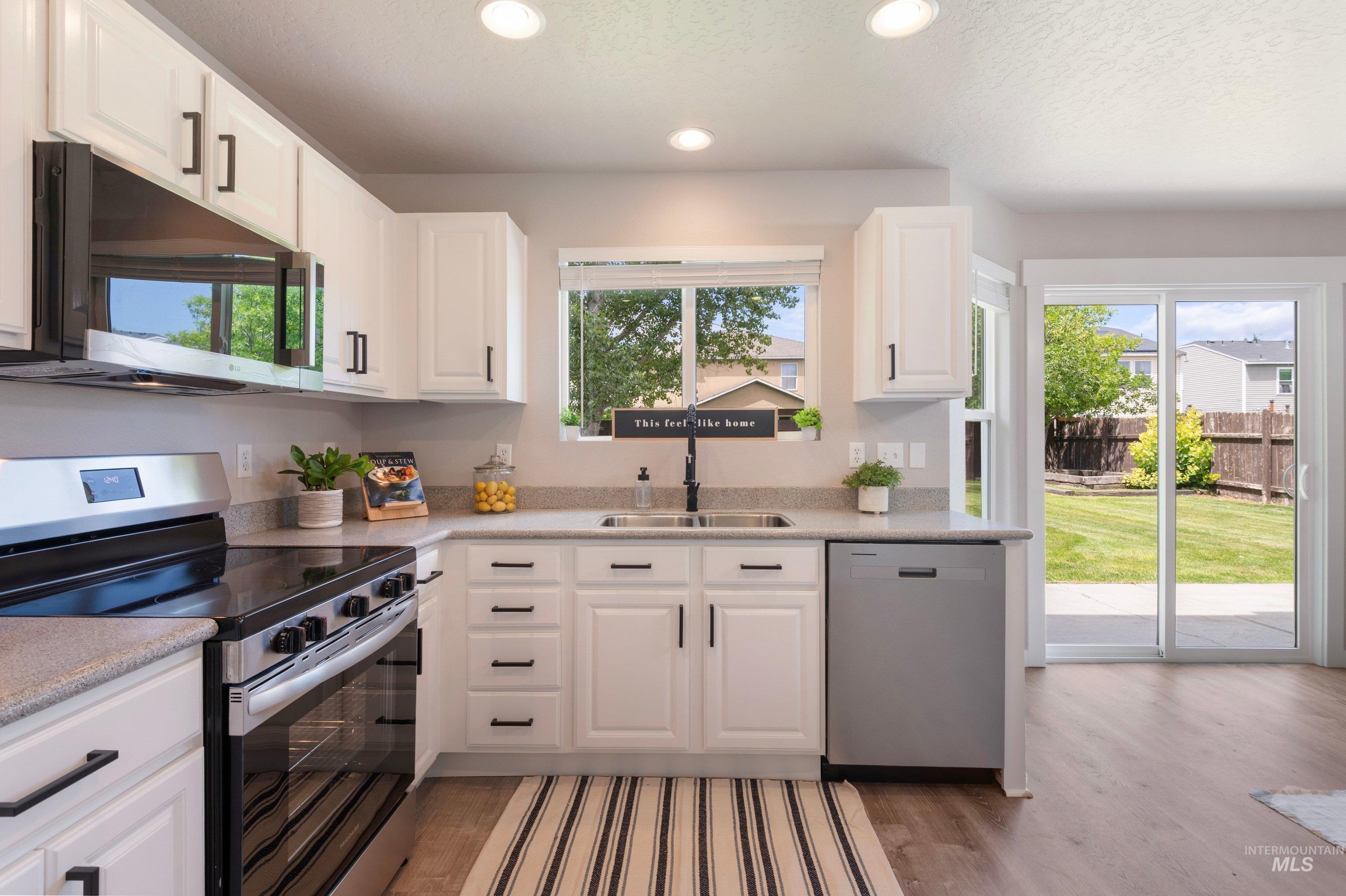 16759 Abram Avenue Caldwell, ID 83607 - Photo 13 of 33 Kitchen featuring white cabinetry, stainless steel appliances, light-toned countertops, and wood-finish flooring