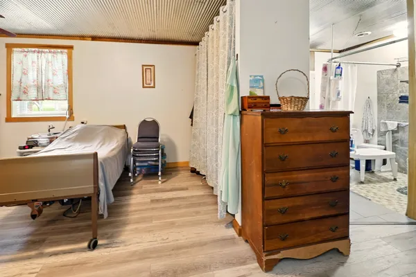 a bedroom with a bed and a chair with the wooden floor