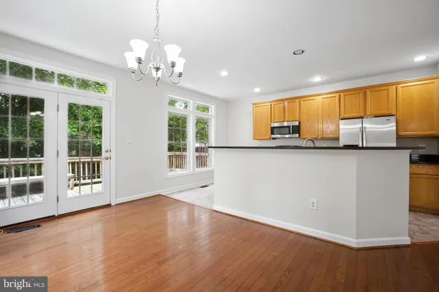 a kitchen with stainless steel appliances granite countertop a sink a microwave oven a refrigerator with wooden floor and cabinets