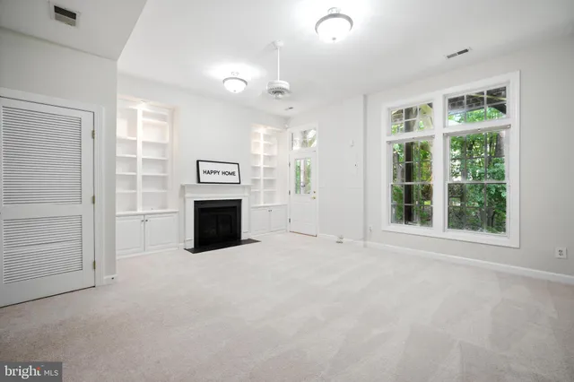 en empty room with windows and fireplace