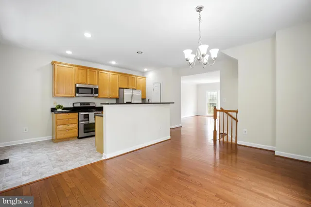 a kitchen with stainless steel appliances granite countertop a stove top oven a sink dishwasher and a refrigerator with wooden floor