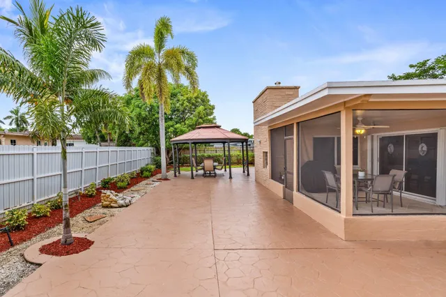 a view of a patio with table and chairs under an umbrella with palm trees