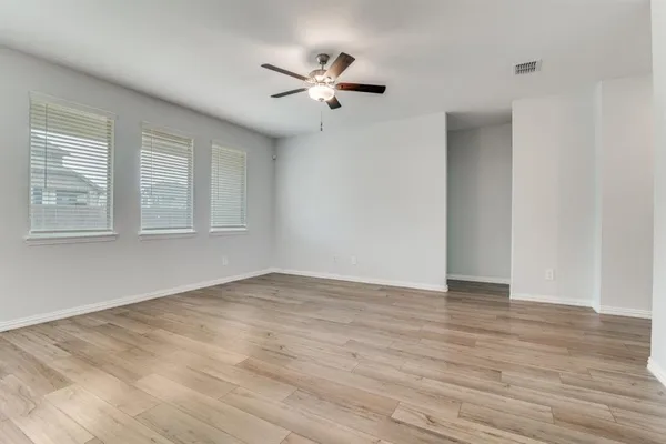 a view of an empty room with wooden floor and a window