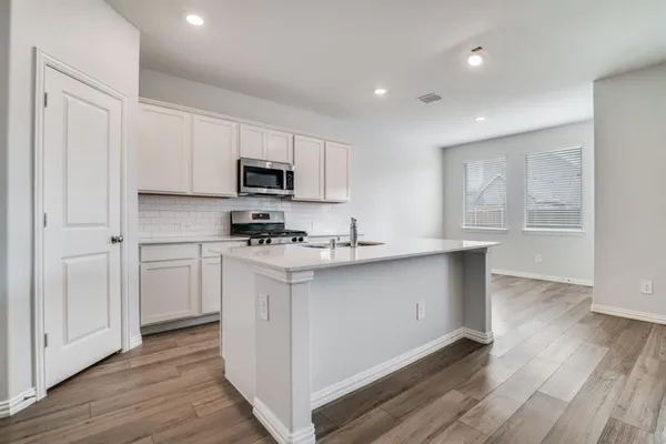 a kitchen with granite countertop white cabinets and black stainless steel appliances