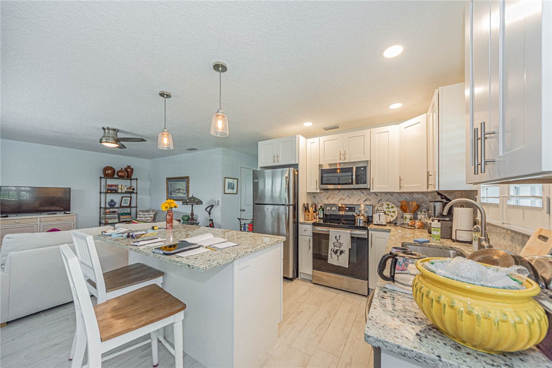 2800 Indian River Boulevard, Unit G6 Vero Beach, FL 32960 - Photo 6 of 22 a kitchen with stainless steel appliances kitchen island granite countertop a sink a stove a refrigerator cabinets and chairs