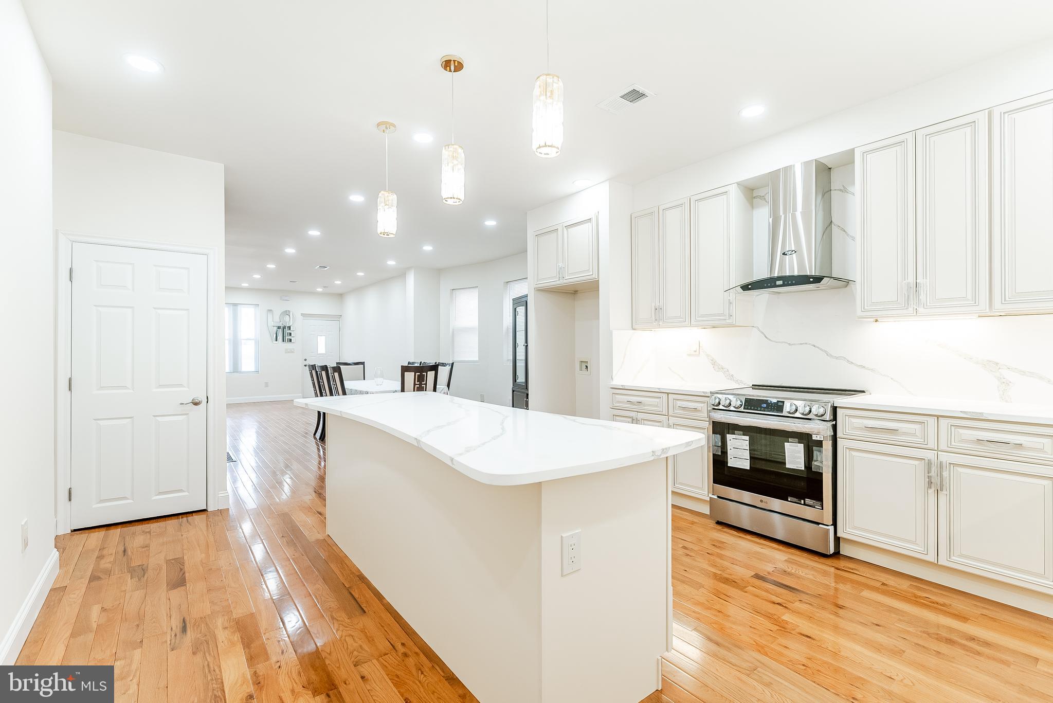 6357 Old York Road Philadelphia, PA 19141 - Photo 11 of 41 a large kitchen with stainless steel appliances kitchen island granite countertop a stove a sink a refrigerator and white cabinets with wooden floor