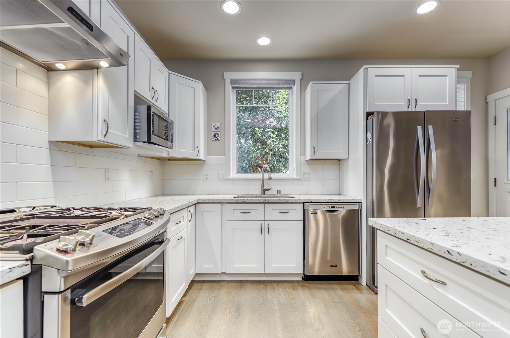 690 Wintersweet Road Northeast Bainbridge Island, WA 98110 - Photo 9 of 23 a kitchen with stainless steel appliances granite countertop a stove a sink dishwasher a refrigerator and a microwave oven with wooden floor