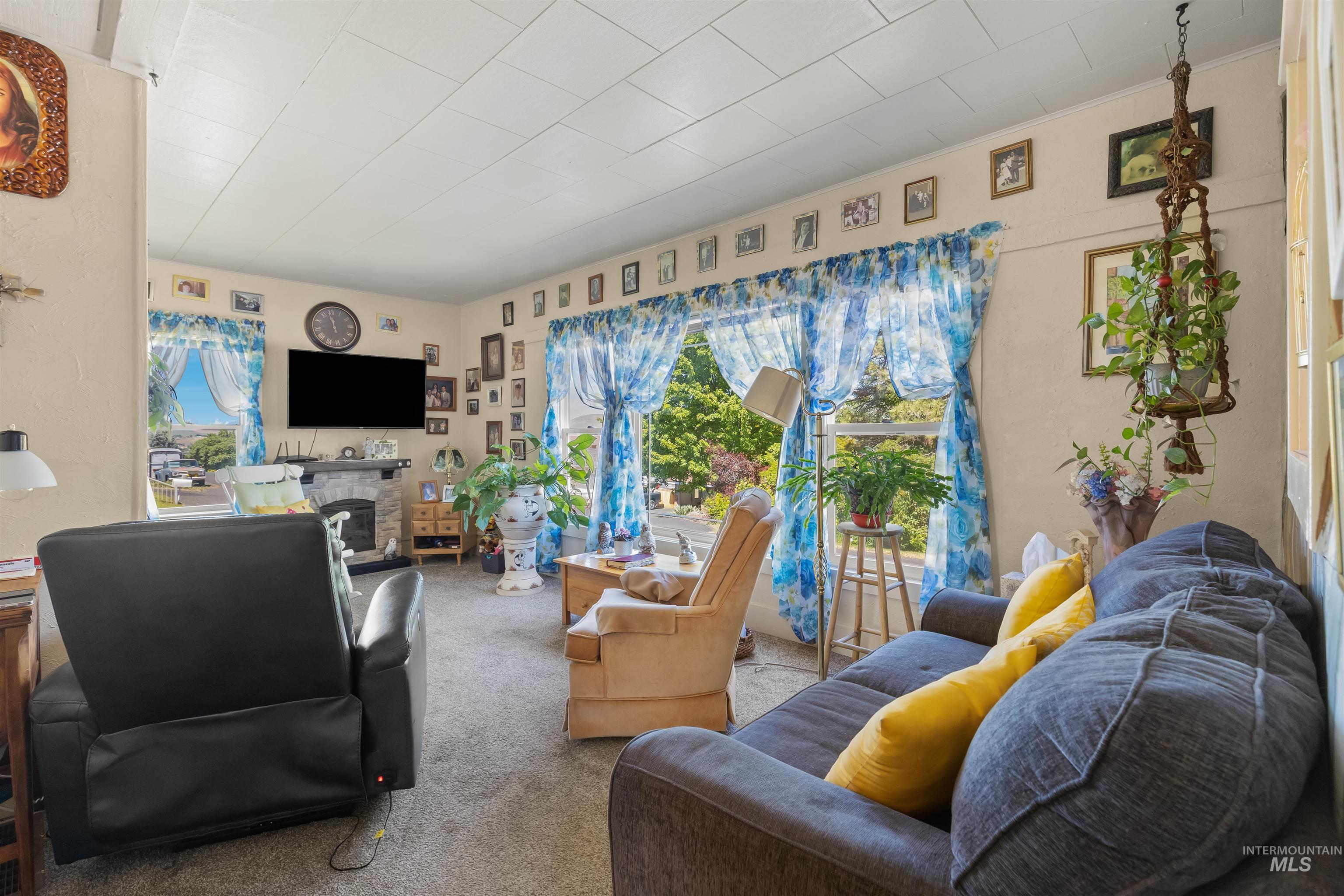 238 Hillcrest Road Lewiston, ID 83501 - Photo 24 of 27 Carpeted living room featuring multiple windows with natural light, a built-in stone fireplace, and light-toned walls