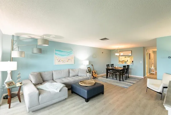 a living room with furniture and a dining table with wooden floor