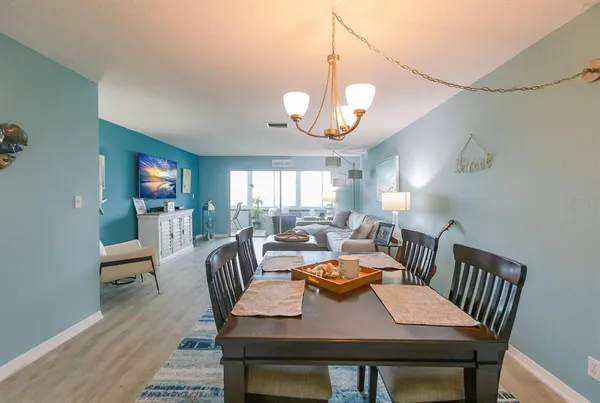 a view of a dining room with furniture a chandelier and wooden floor