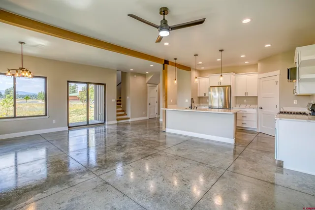 a view of a hallway with stainless steel appliances kitchen island granite countertop a refrigerator and a stove top oven