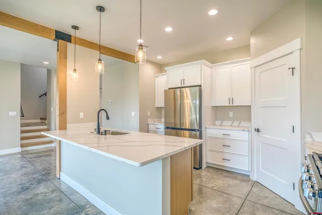 a large kitchen with stainless steel appliances granite countertop a sink a stove and a refrigerator